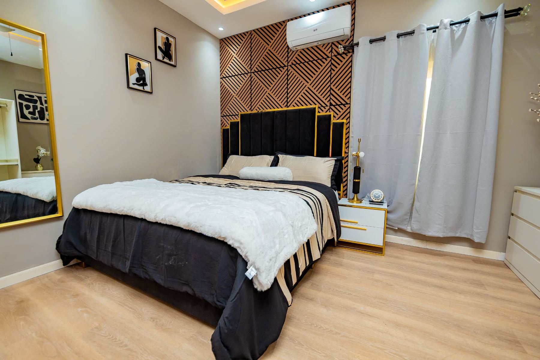 Penthouse bedroom with black and gold velvet headboard and geometric feature wall