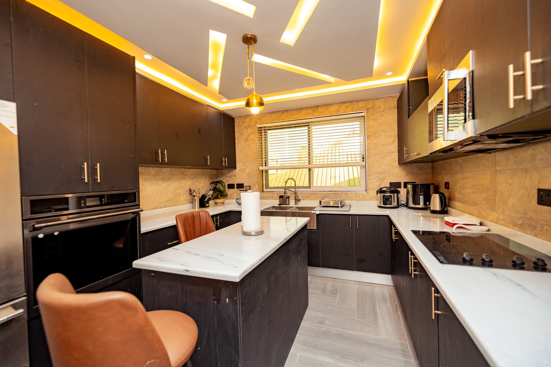 Dark timber kitchen with marble island and warm cove lighting
