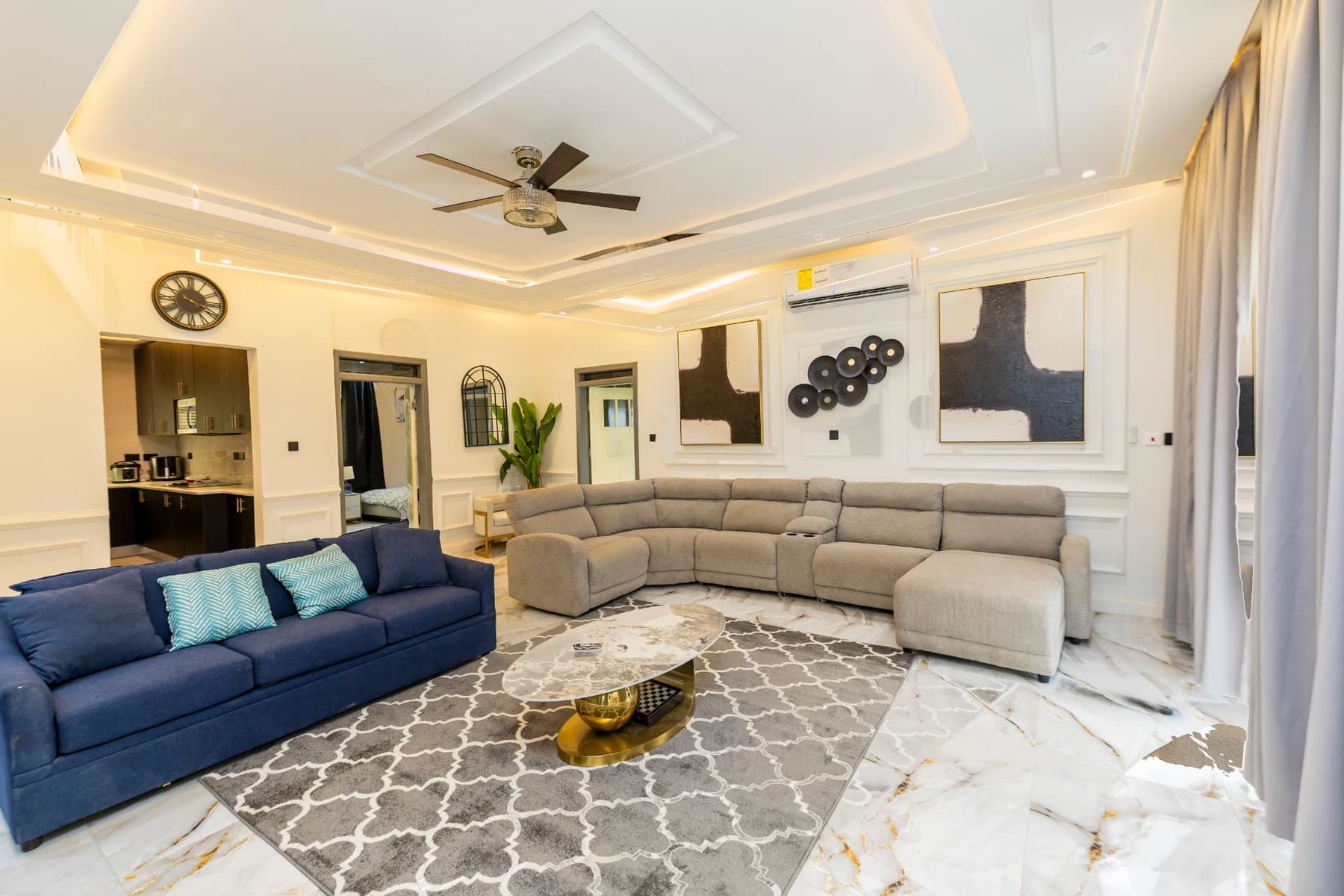 Unit 107 open living and dining space with sectional and navy sofa beside the kitchen