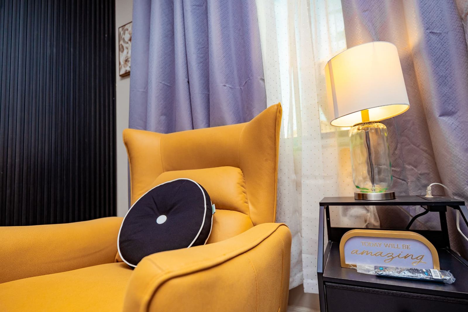 Mustard wingback reading chair beside a glass lamp in the two-bedroom