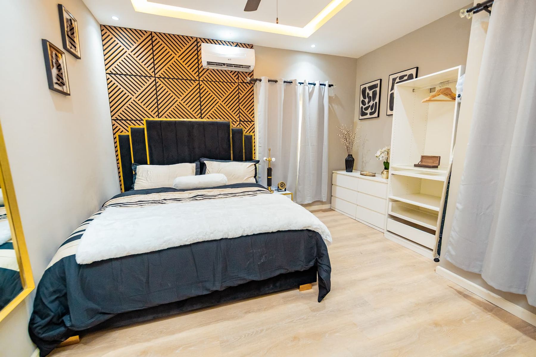 Penthouse bedroom with open wardrobe, dresser and gold-framed mirror