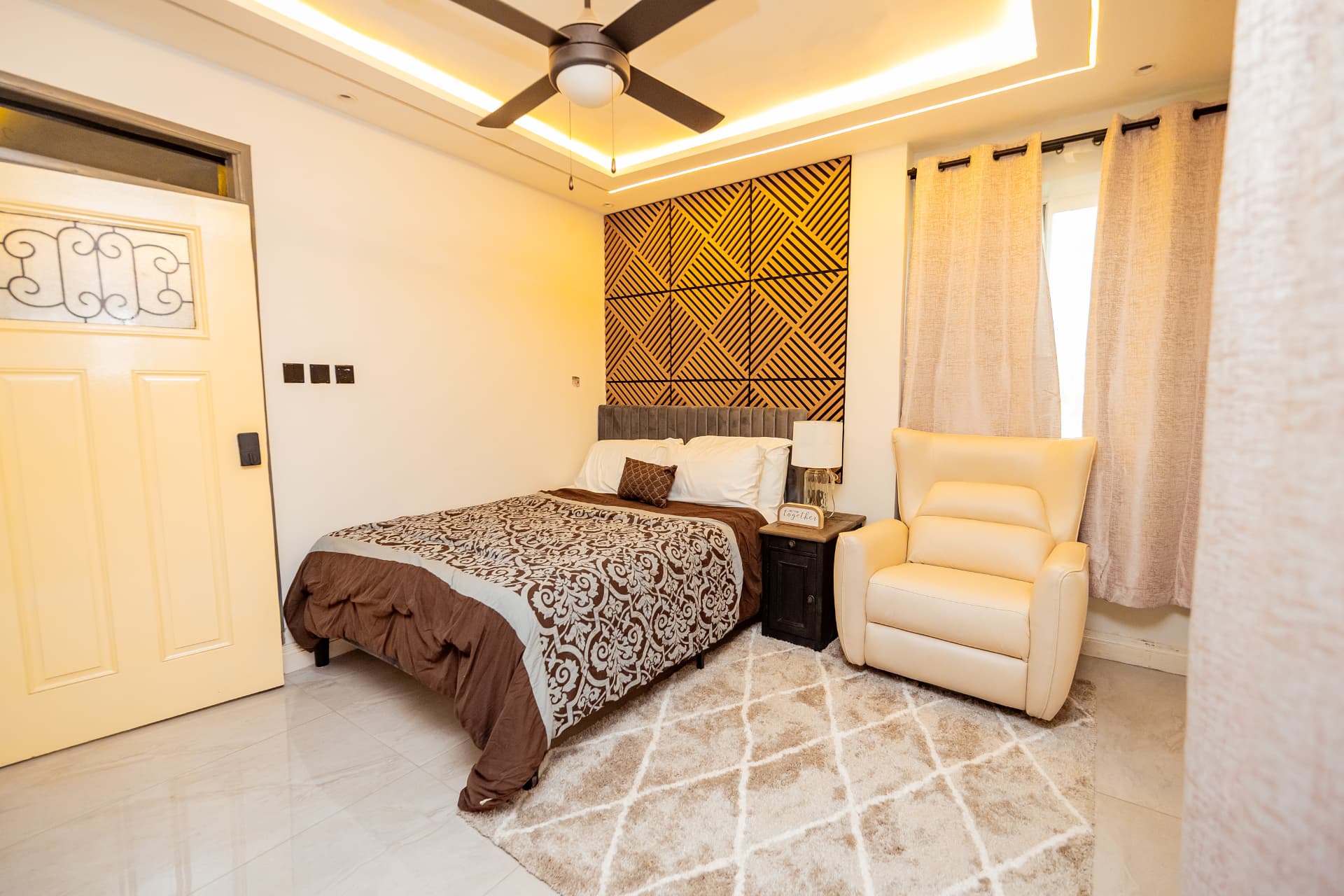 Queen bedroom with slatted feature wall and reading chair