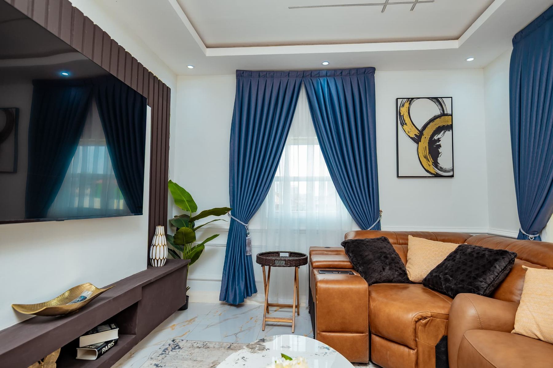 Penthouse lounge with leather sectional, blue curtains and abstract art