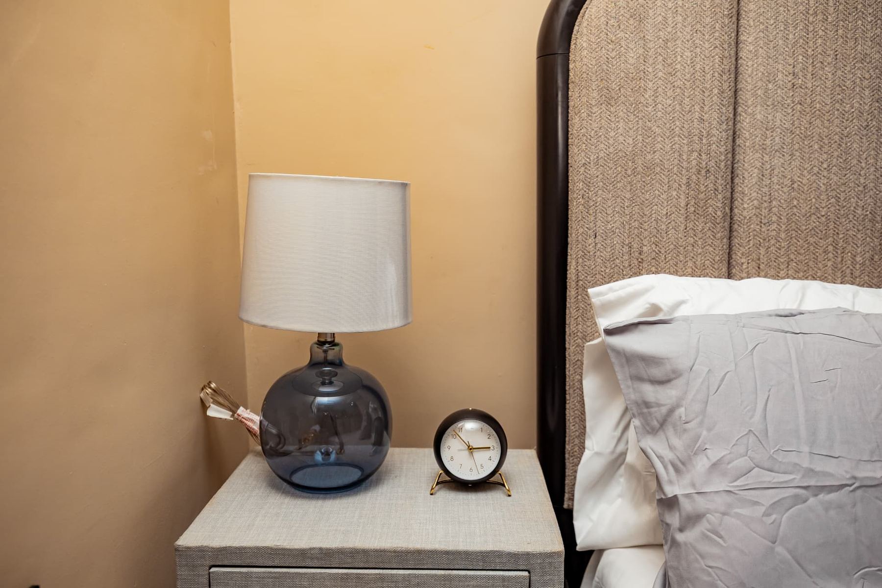 Bedside table with smoked glass lamp and brass alarm clock in Unit 106