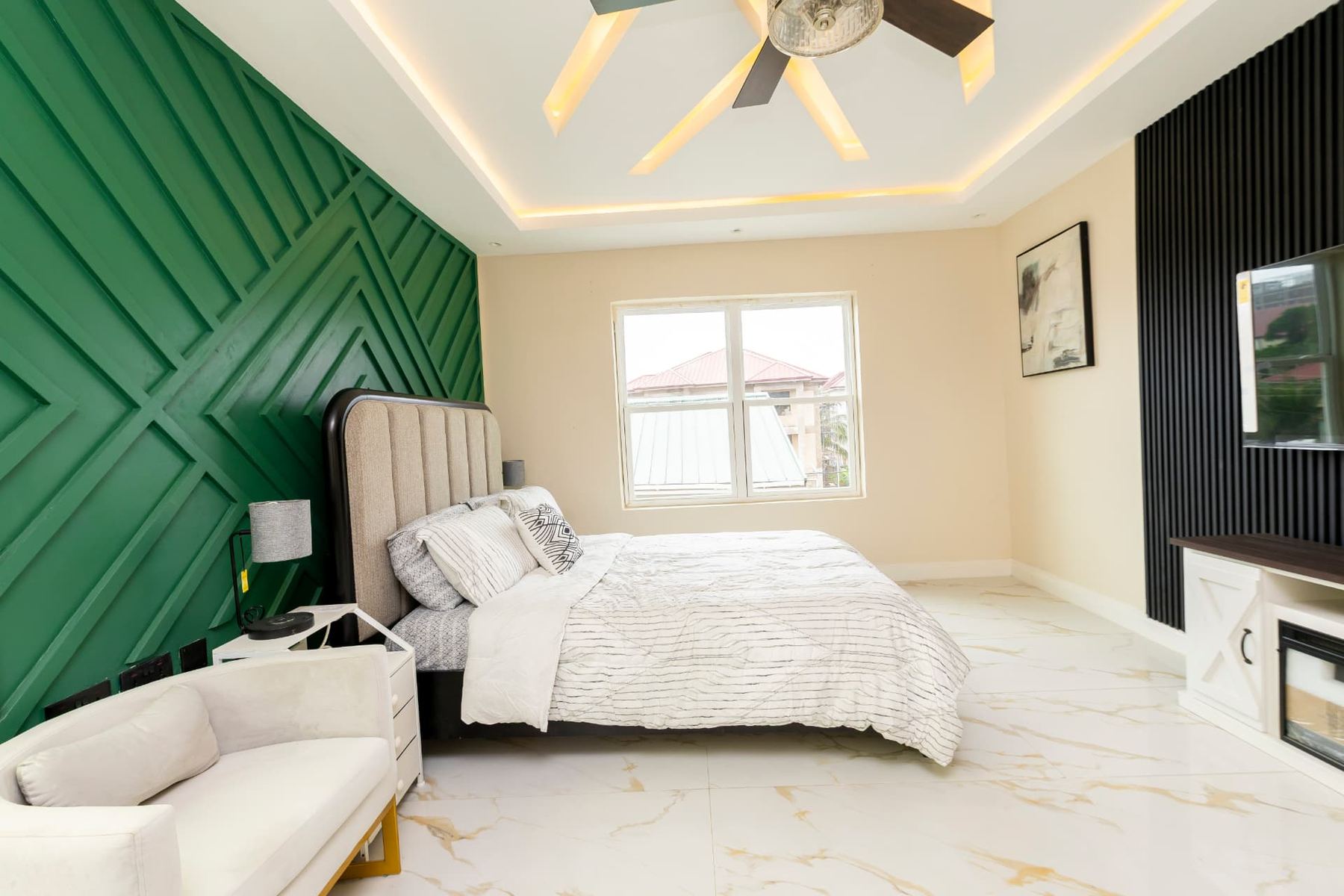 Unit 107 second bedroom with emerald panelled feature wall, queen bed and smart TV