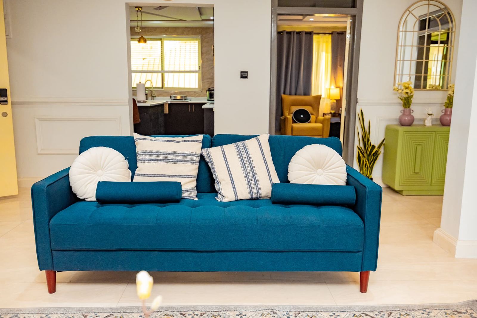 Two-bedroom apartment living room with teal sofa and open kitchen