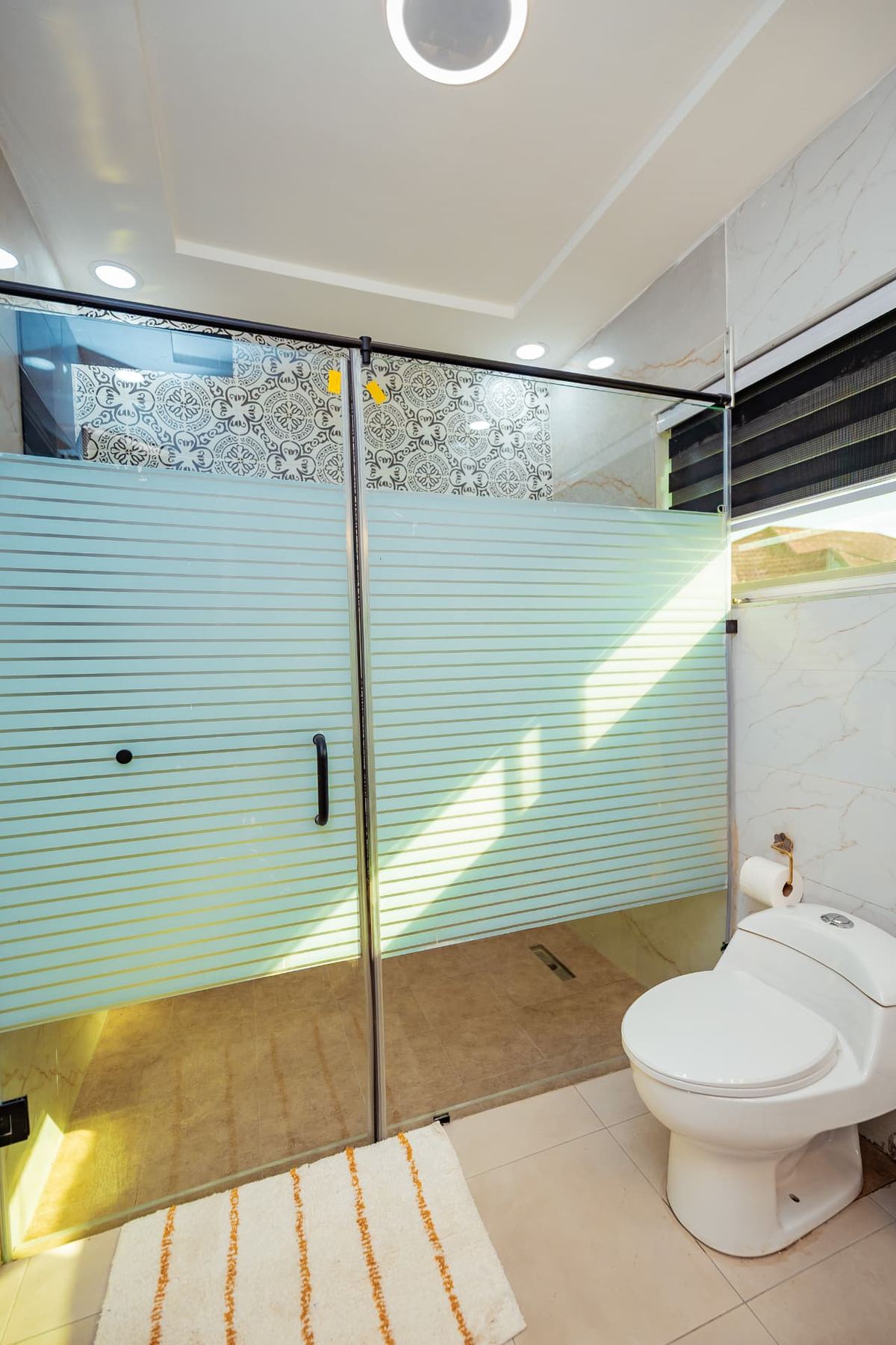 Unit 107 bathroom with frosted glass walk-in shower and patterned tile feature