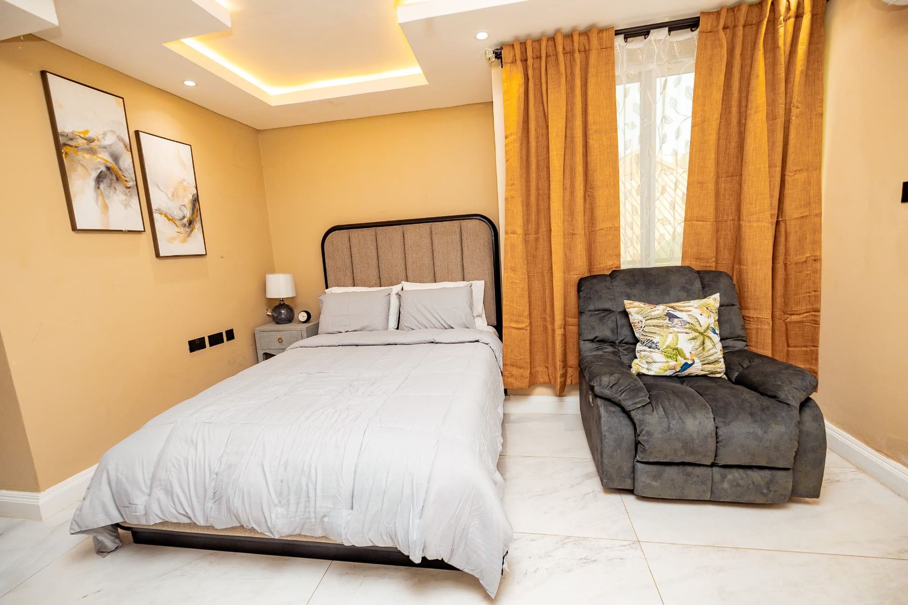 Unit 106 bedroom with queen bed, recliner armchair and gold curtains